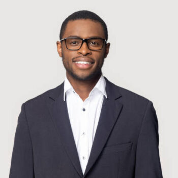 Smiling african American millennial businessman in glasses isolated on grey studio background posing, satisfied successful black male in formal suit wearing spectacles look at camera laughing